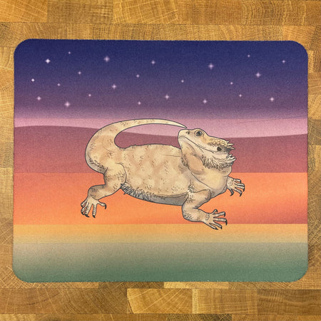 A mousepad decorated with an illustration f a bearded dragon lizard on an abstract dessert landscape background.