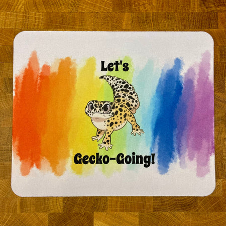 Placemat with a cartoon gecko and rainbow design on a wooden surface