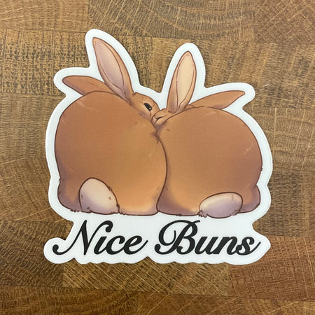 Sticker of two rabbits with 'Nice Buns' text photographed on a wooden background