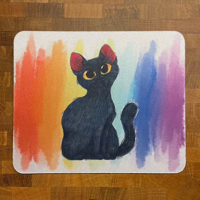 A mousepad with an illustration of a cute black cat n a rainbow color watercolor background.