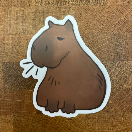 sticker of a cartoon illustration of a sitting capybara photographed on wood background